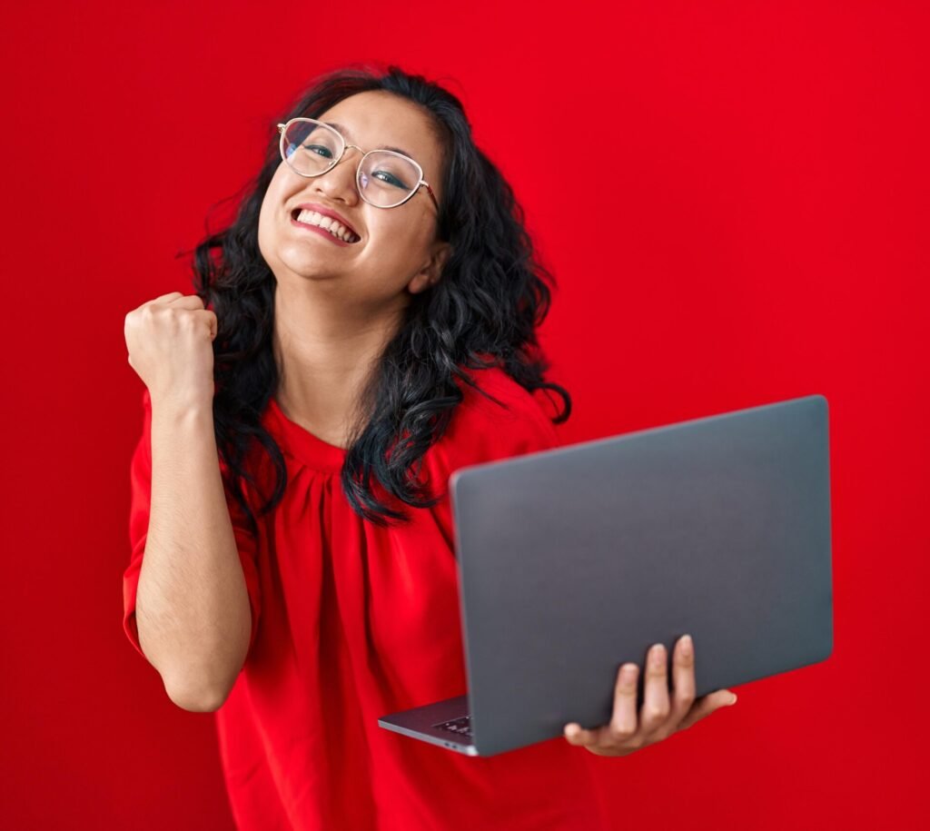 young asian woman working using computer laptop celebrating victory with happy smile winner expression with raised hands 1 scaled e1766211296434